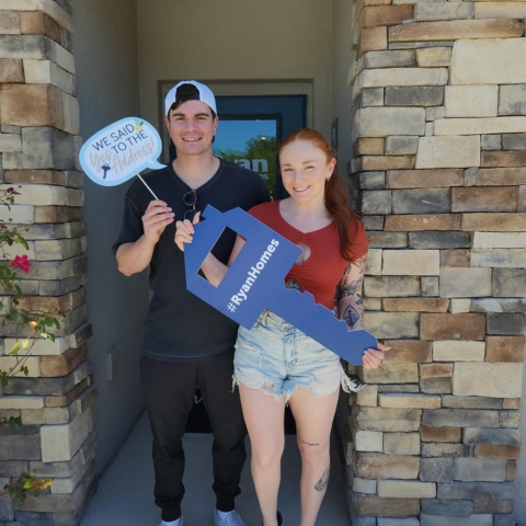 Couple celebrating new home purchase with Ryan Homes, holding a large key-shaped sign