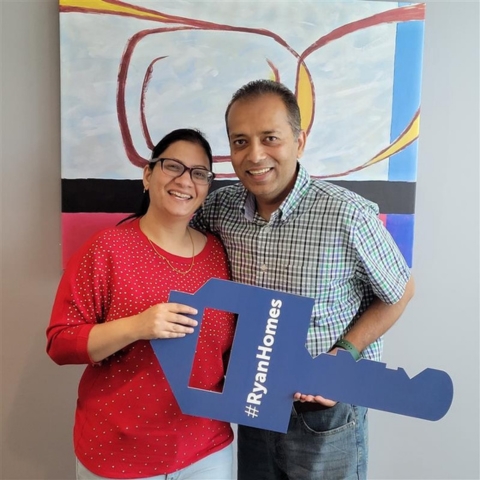 Happy couple celebrating their new Ryan Homes purchase, holding a branded key-shaped sign