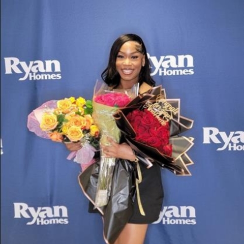 New Ryan Homes buyer celebrating home purchase, holding vibrant flower bouquets 