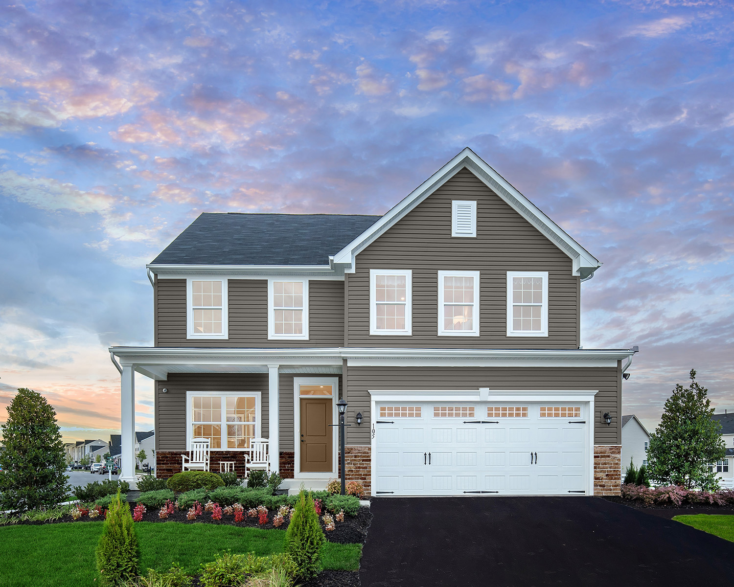 Two-story gray suburban home with white trim, dark shingle roof, front porch and double garage